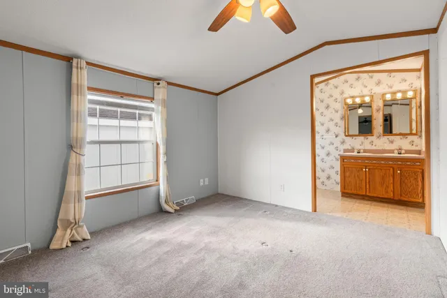 an empty room with chandelier fan and windows