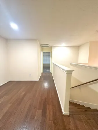 an empty room with wooden floor chandelier fan and windows