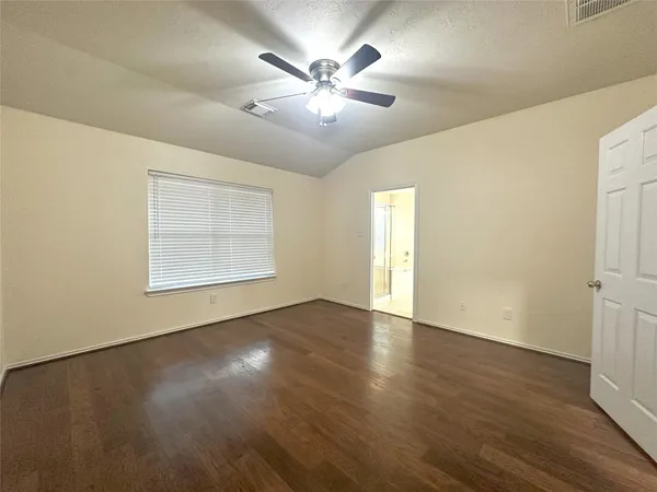 an empty room with wooden floor chandelier fan and windows