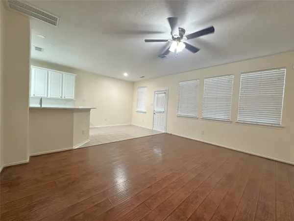 a view of an empty room with chandelier fan and wooden floor