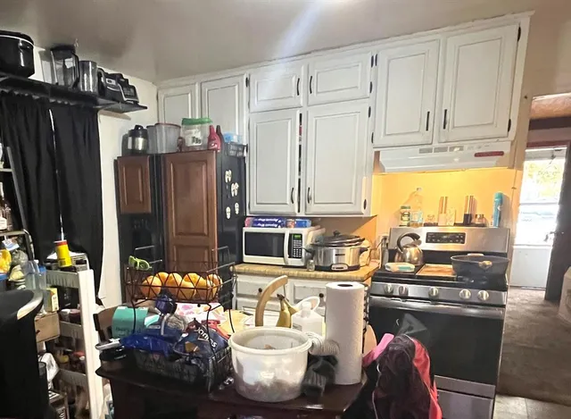 a room with stainless steel appliances kitchen island granite countertop a refrigerator and a stove top oven