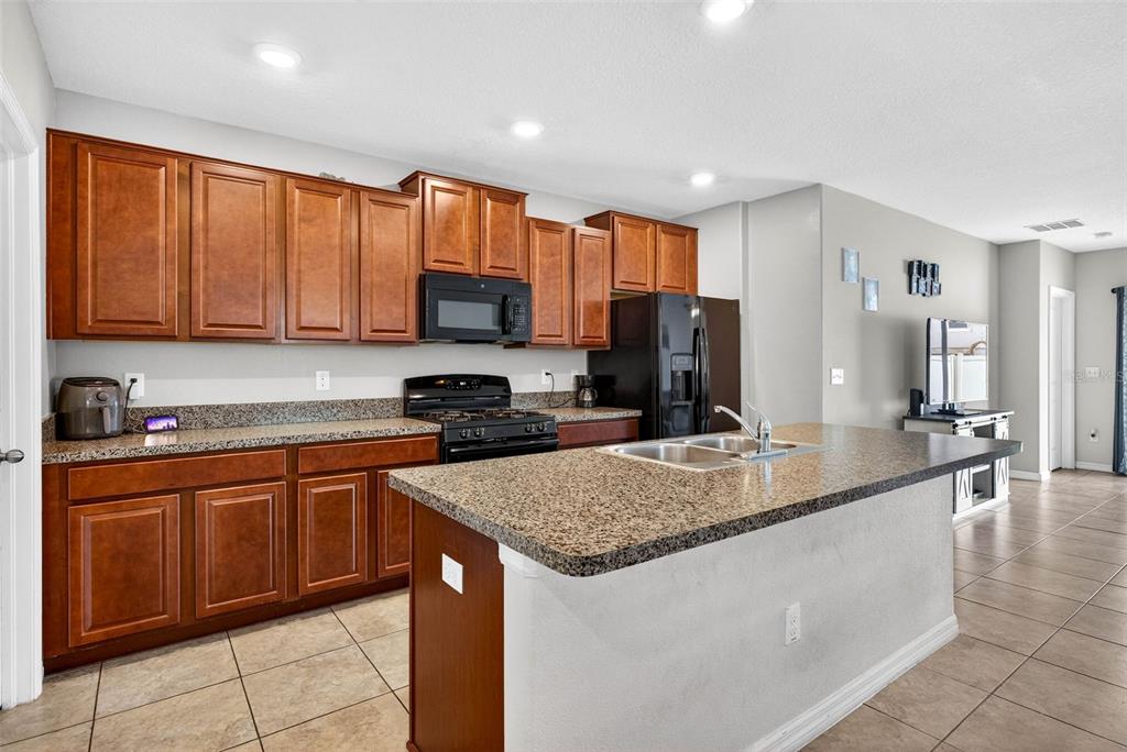 9616 Lemon Drop Loop Sun City Center, FL 33573 - Photo 10 of 53 a kitchen with kitchen island granite countertop a sink counter top space appliances and cabinets