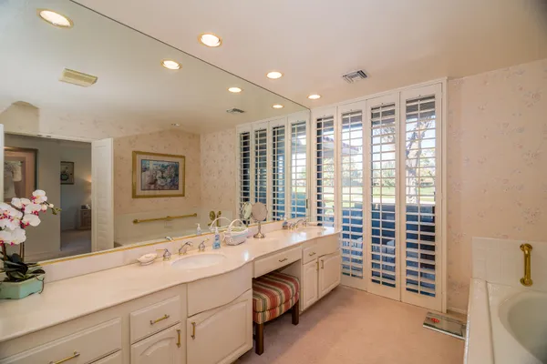 a spacious bathroom with double vanity and a large mirror