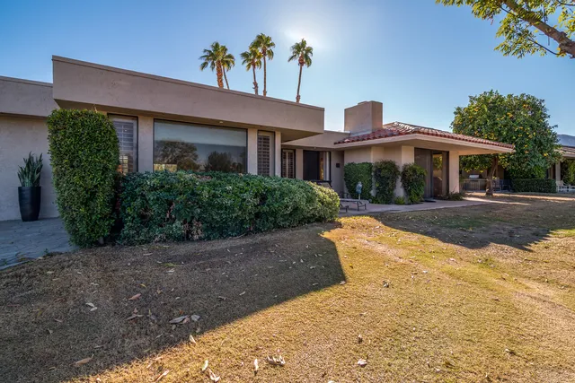 a front view of a house with a yard and potted plants