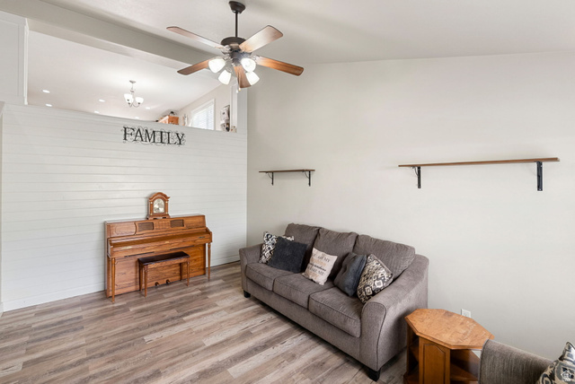 2485 South 1100th Street West Logan, UT 84321 - Photo 10 of 53 Spacious living area featuring wood-finish flooring, a white shiplap accent wall, and a ceiling fan with light fixture