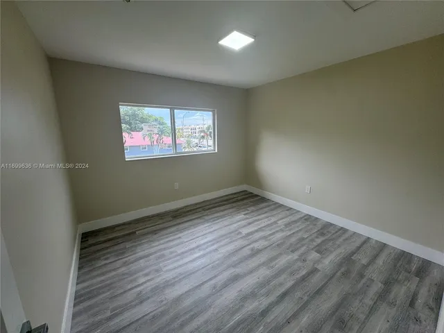 an empty room with wooden floor and window