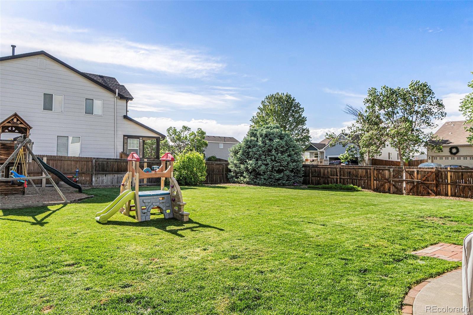 7395 Hickory Circle Frederick, CO 80504 - Photo 23 of 23 a view of a backyard with a slide trees and wooden fence