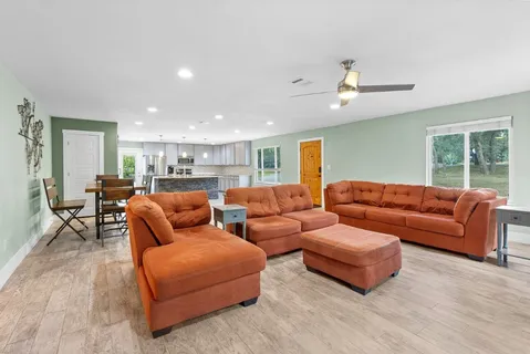 a living room with furniture kitchen view and a chandelier