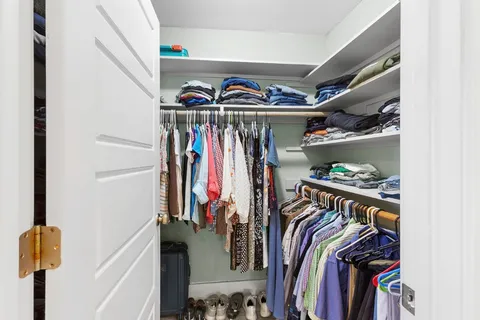 a view of walk in closet with clothes and shoes