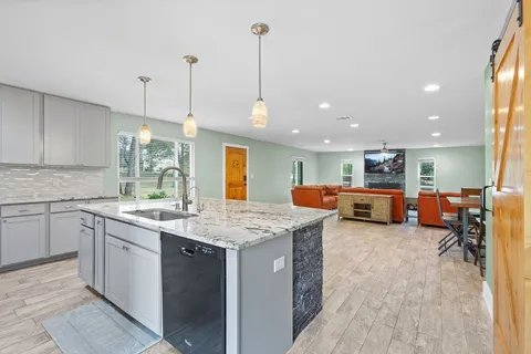 a kitchen with stainless steel appliances granite countertop lots of counter space sink and living room view