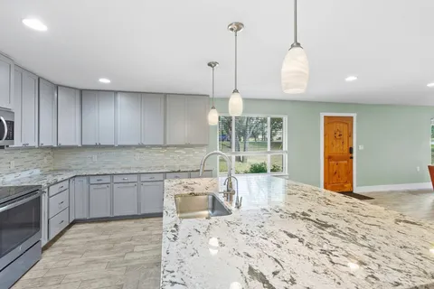a kitchen with granite countertop sink and wooden floor