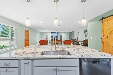 a kitchen with granite countertop kitchen island a sink and a large window