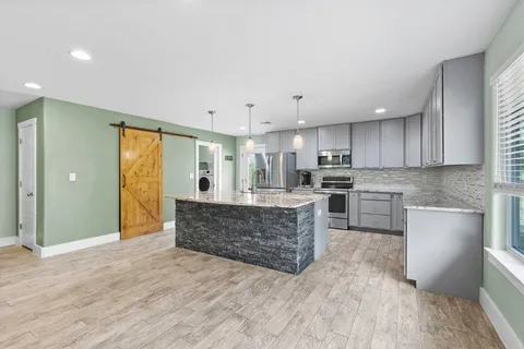 a large kitchen with kitchen island a sink stainless steel appliances and cabinets