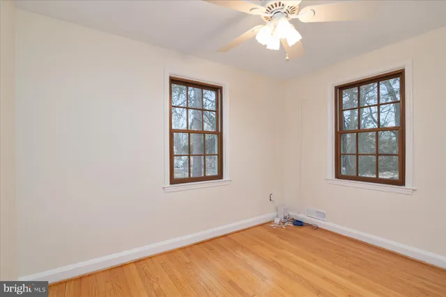 an empty room with chandelier fan and windows
