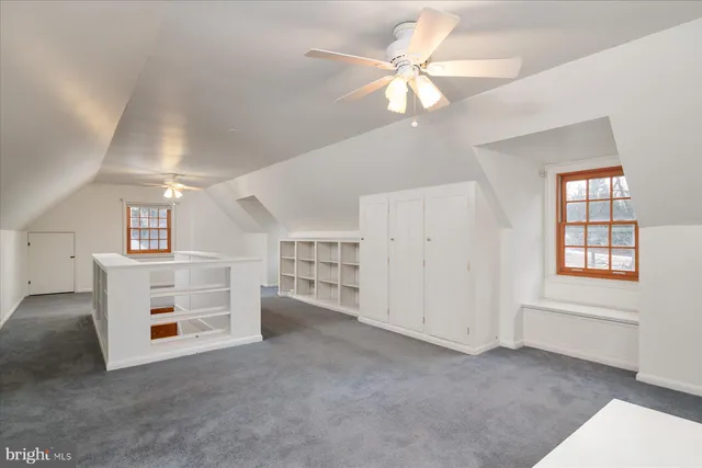 a view of a livingroom with a chandelier fan and windows