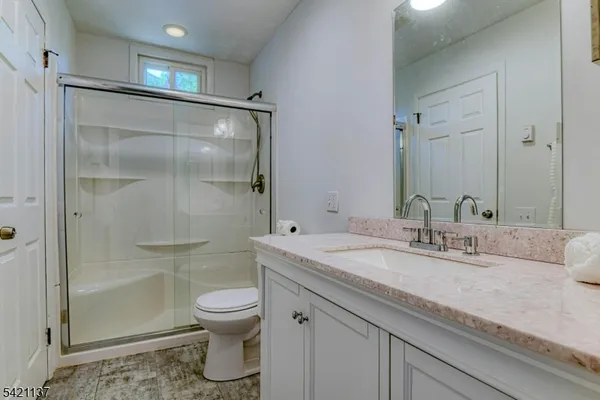 a bathroom with a granite countertop sink a toilet and shower