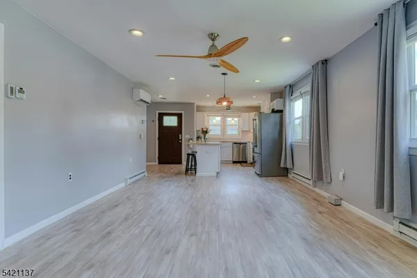 an empty room with wooden floor ceiling fan and windows