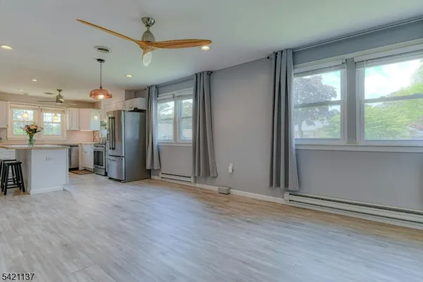 an empty room with wooden floor and a kitchen