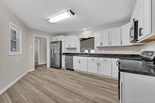 a kitchen with granite countertop white cabinets and stainless steel appliances