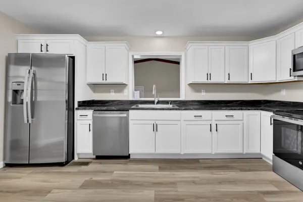 a kitchen with granite countertop white cabinets and stainless steel appliances