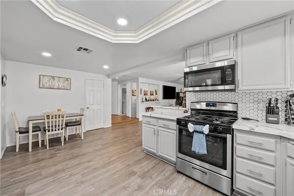 a kitchen with stainless steel appliances kitchen island granite countertop a stove and a wooden floors
