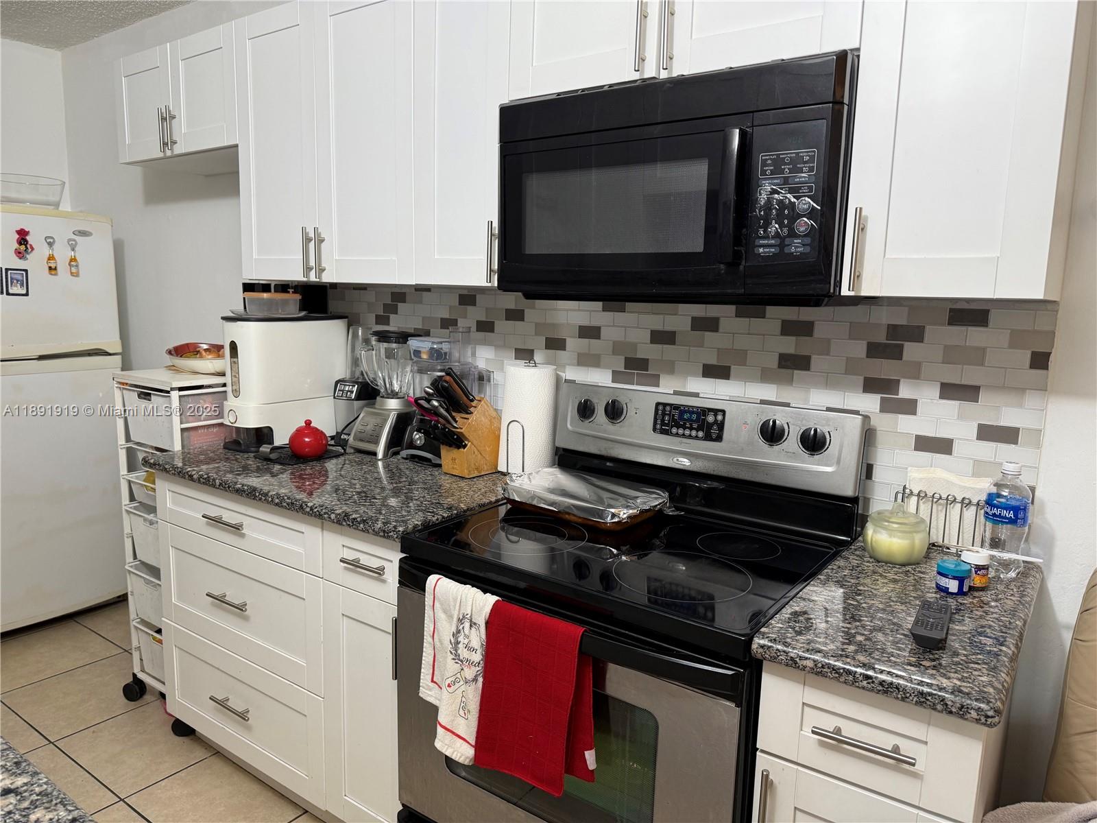 1100 Northeast 1st Court, Unit 120 Hallandale Beach, FL 33009 - Photo 3 of 45 a kitchen with stainless steel appliances granite countertop a stove and a microwave