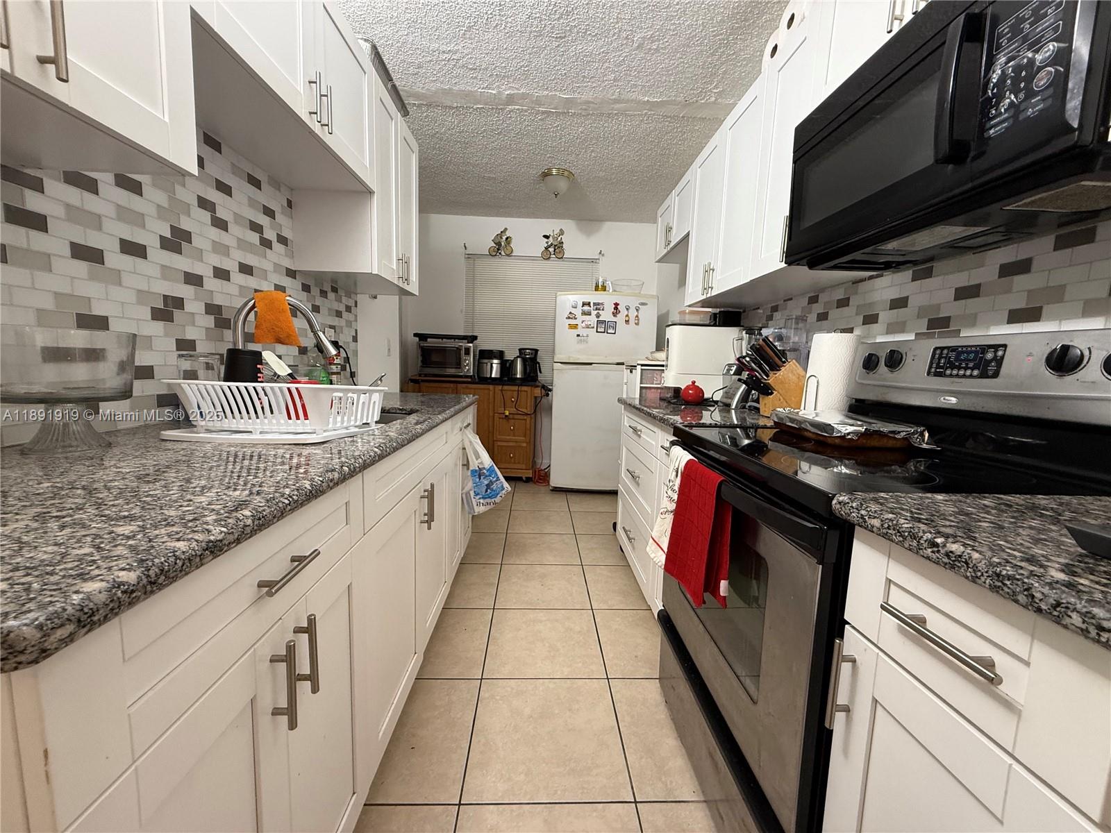 1100 Northeast 1st Court, Unit 120 Hallandale Beach, FL 33009 - Photo 37 of 45 a kitchen with stainless steel appliances granite countertop a stove a sink and a microwave