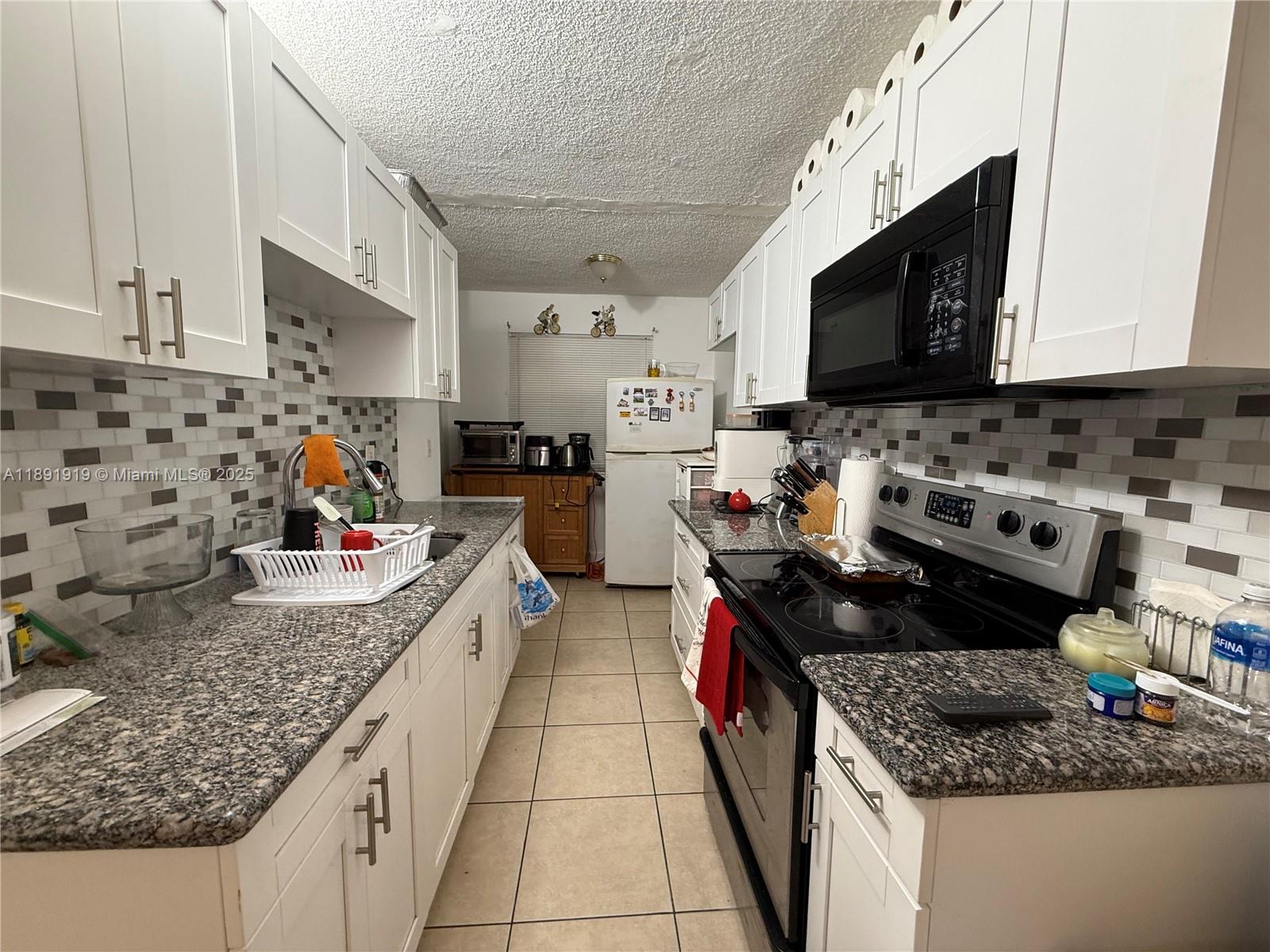 1100 Northeast 1st Court, Unit 120 Hallandale Beach, FL 33009 - Photo 4 of 45 a kitchen with stainless steel appliances granite countertop a sink stove and refrigerator