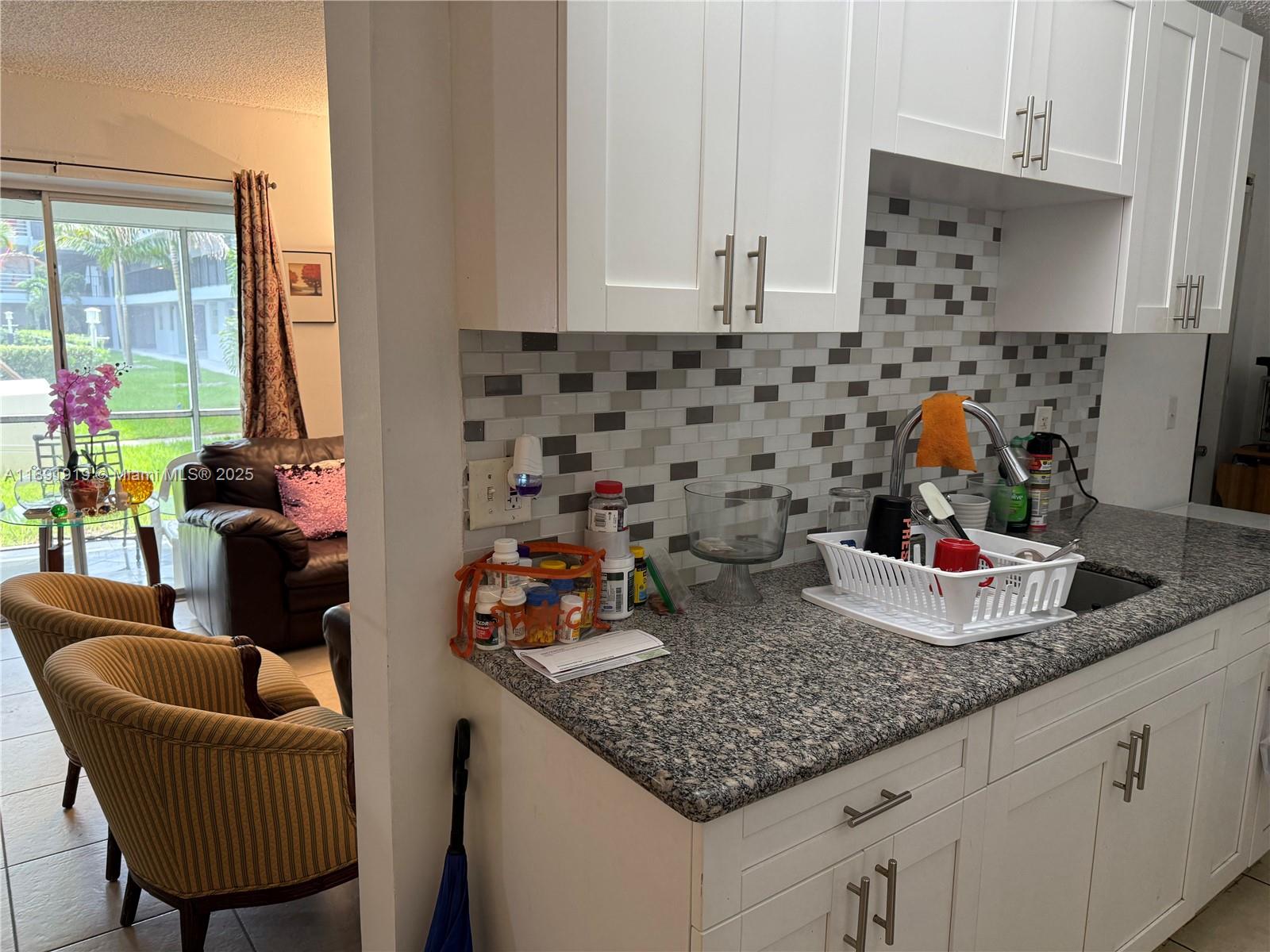 1100 Northeast 1st Court, Unit 120 Hallandale Beach, FL 33009 - Photo 6 of 45 a kitchen with granite countertop a sink a stove and white cabinets
