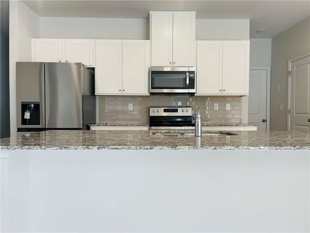 a kitchen with stainless steel appliances granite countertop a refrigerator a stove a microwave and a sink