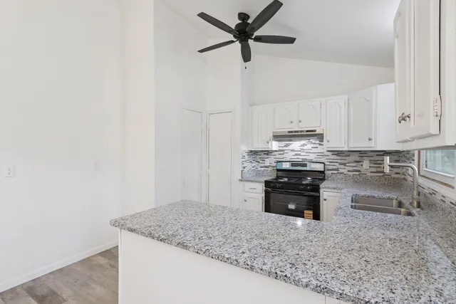 a kitchen with stainless steel appliances granite countertop a sink stove and cabinets