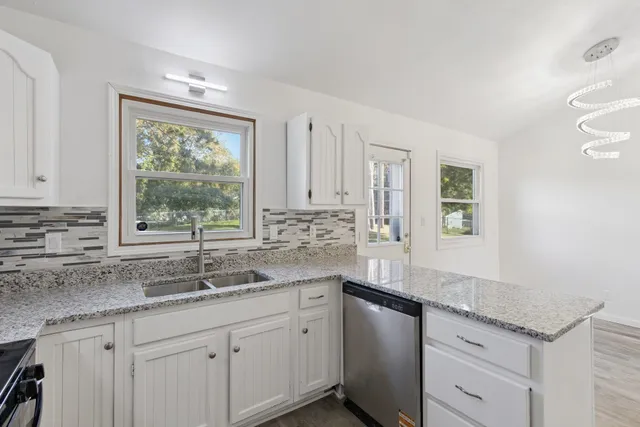 a kitchen with granite countertop kitchen island white cabinets and a window