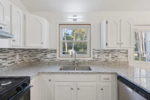 a kitchen with granite countertop white cabinets and a window