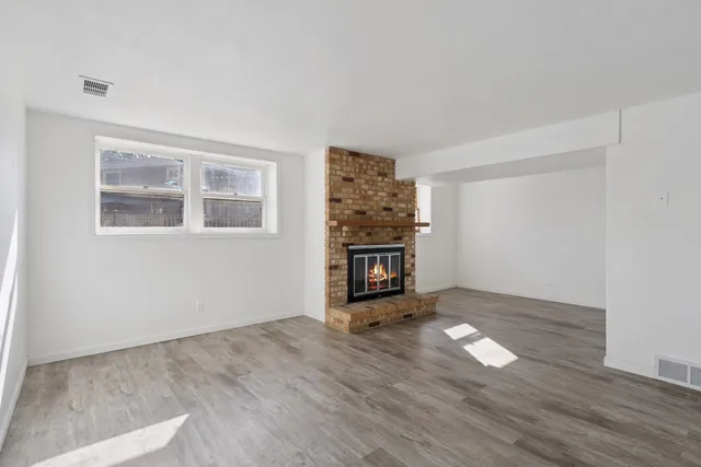 a view of an empty room with a window and wooden floor