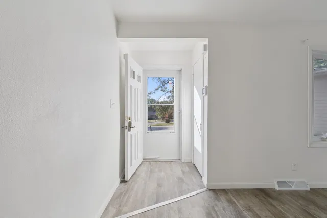 a view of a hallway with wooden floor and a bathroom