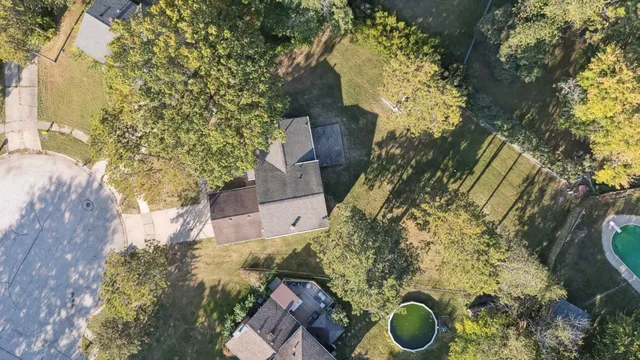 a backyard of a house with large trees and plants