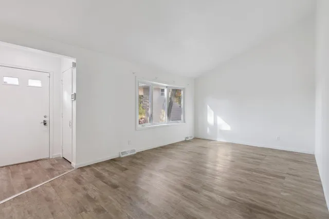 a view of an empty room with window and wooden floor