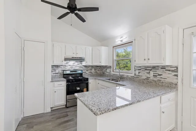 a kitchen with granite countertop stainless steel appliances granite countertop a stove a sink and a refrigerator