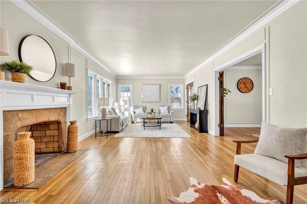 3145 Huntington Road Shaker Heights, OH 44120 - Photo 6 of 28 Spacious living area featuring polished wood-finish flooring, a stone-faced fireplace with a white mantel, multiple windows, and crown molding