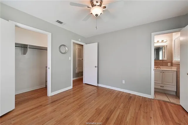 an empty room with wooden floor and a ceiling fan