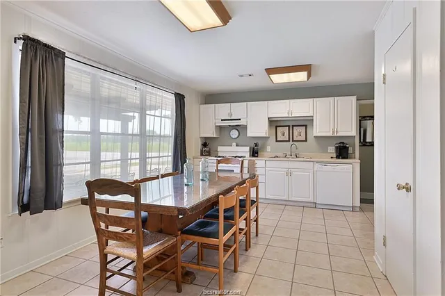a kitchen with a dining table chairs and white appliances