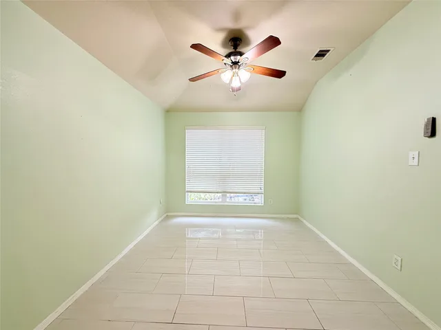 a view of an empty room with chandelier fan and fire place