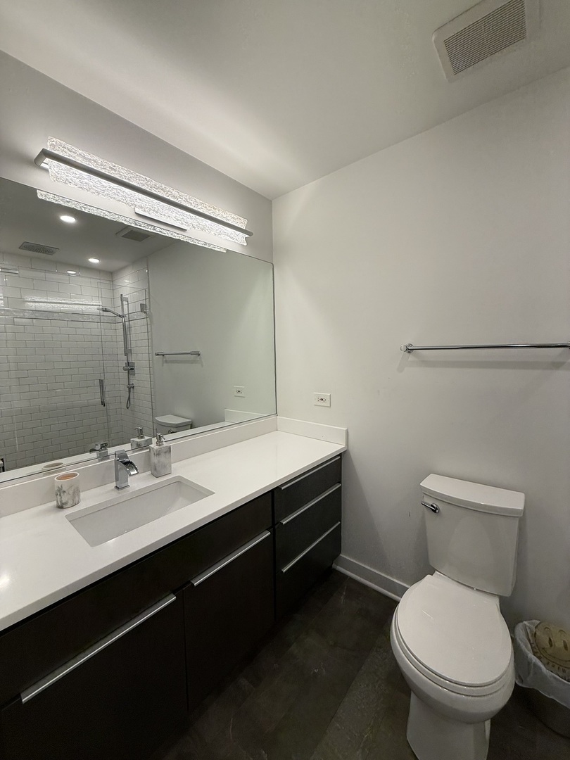 222 South Racine Avenue, Unit 207 Chicago, IL 60607 - Photo 25 of 29 a bathroom with a toilet sink and mirror