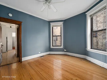 a view of empty room with wooden floor and fan