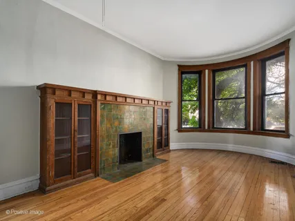 an empty room with wooden floor fireplace and windows