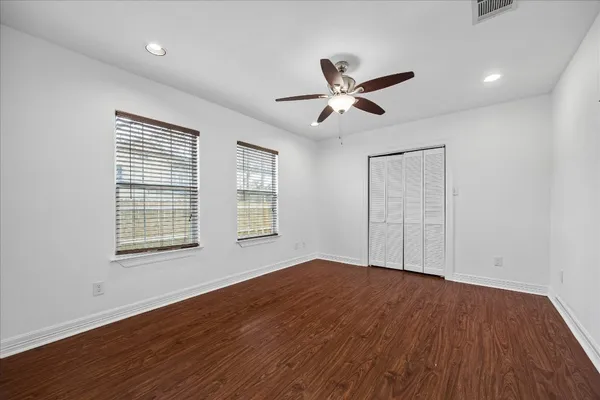 a view of empty room with wooden floor and fan