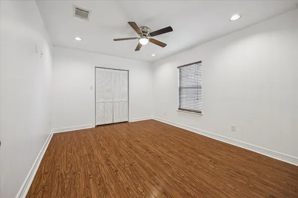 a view of empty room with wooden floor and fan