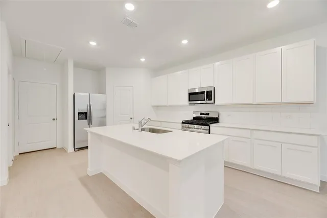 a kitchen with stainless steel appliances a refrigerator sink and white cabinets