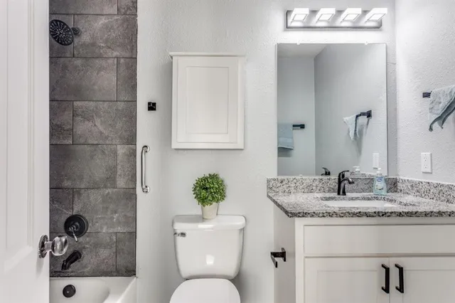 a bathroom with a granite countertop sink a toilet and shower