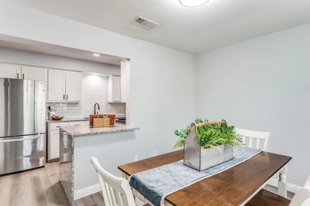 a kitchen with stainless steel appliances granite countertop a refrigerator a stove a sink dishwasher and white cabinets with wooden floor